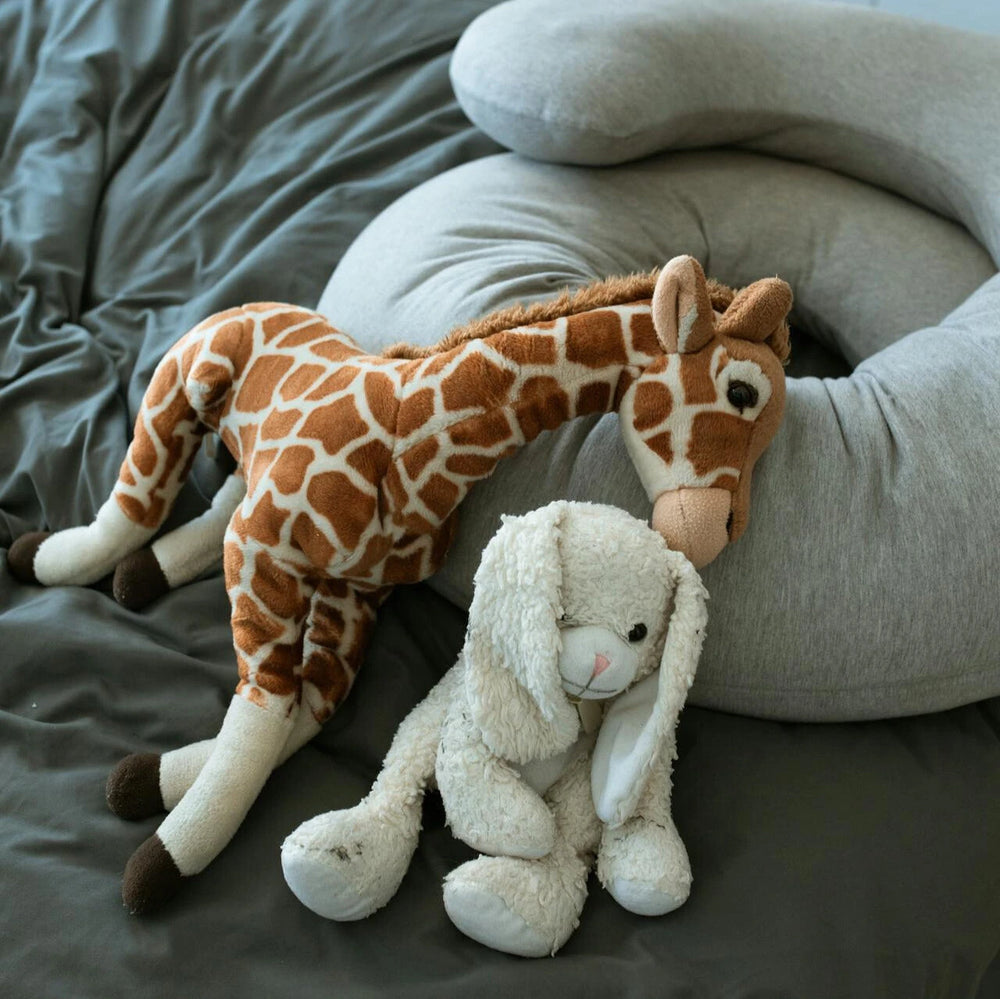 Stuffed giraffe and bunny toys on bed