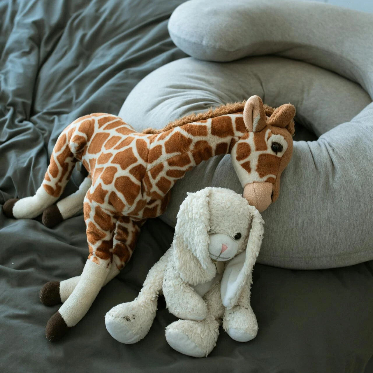 Stuffed giraffe and bunny toys on bed