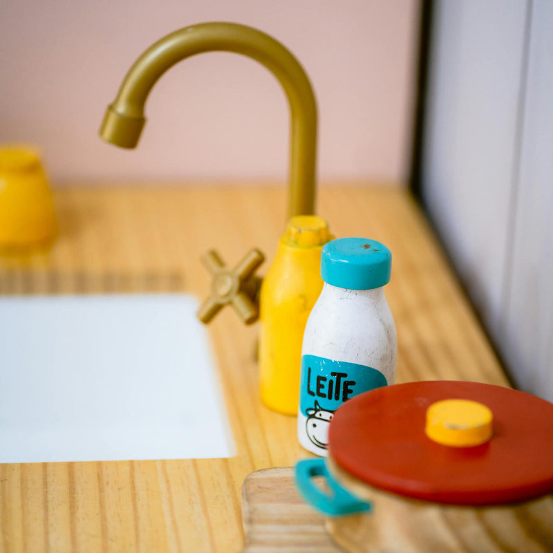 Toy kitchen sink with bottle and utensils on countertop